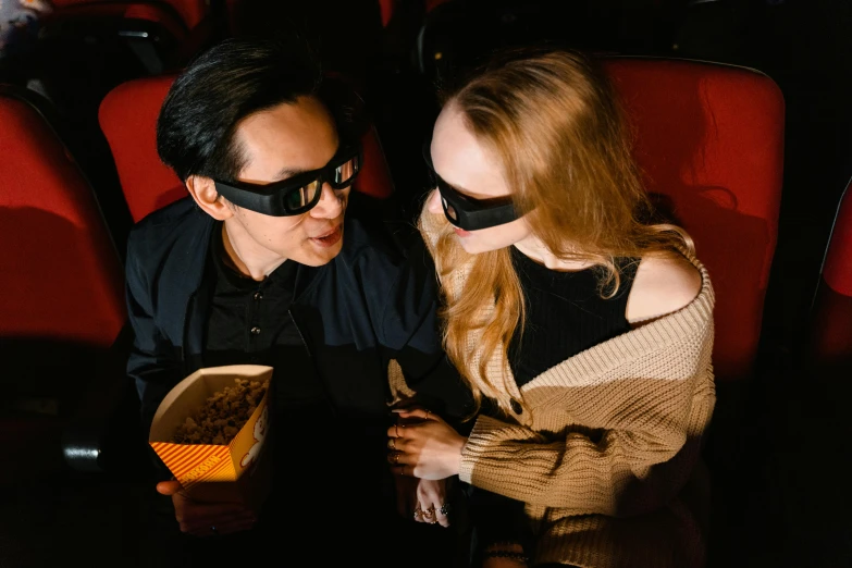 a man wearing blind folds standing next to a girl in a movie theater