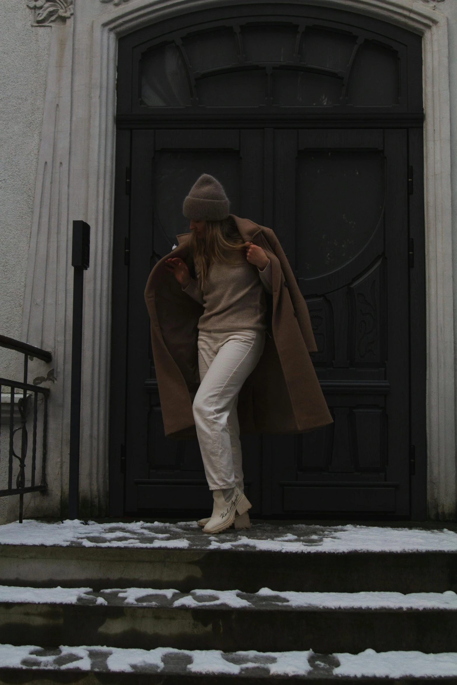 a woman in a coat is standing in front of a door