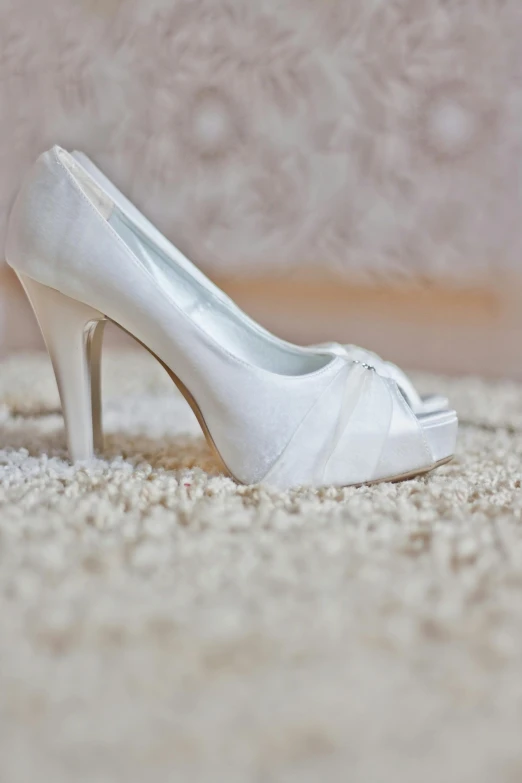 the white high heel shoe is decorated with satin