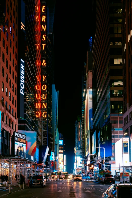 a street with cars in the middle is lit up at night