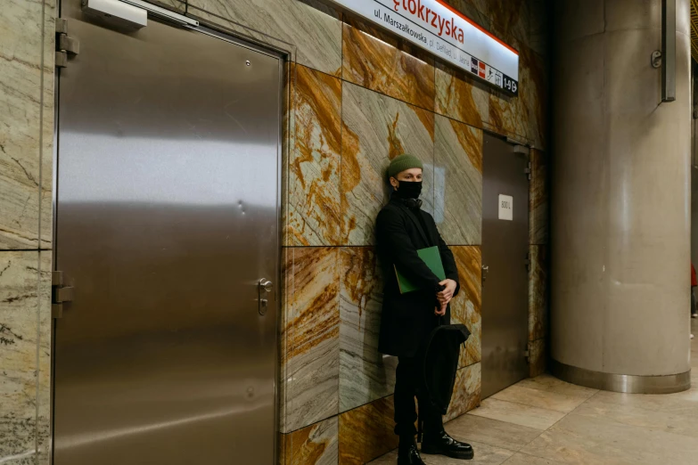 a man stands in an elevator in a black outfit