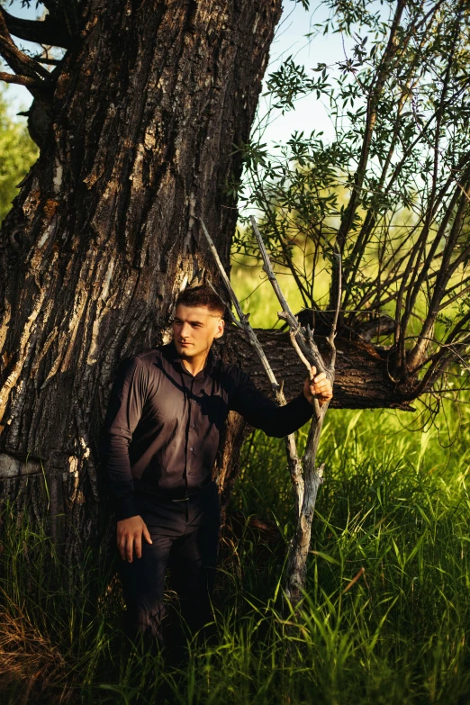 man with rifle leaning against tree trunk