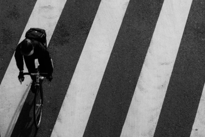 a man riding on top of a bike across a cross walk