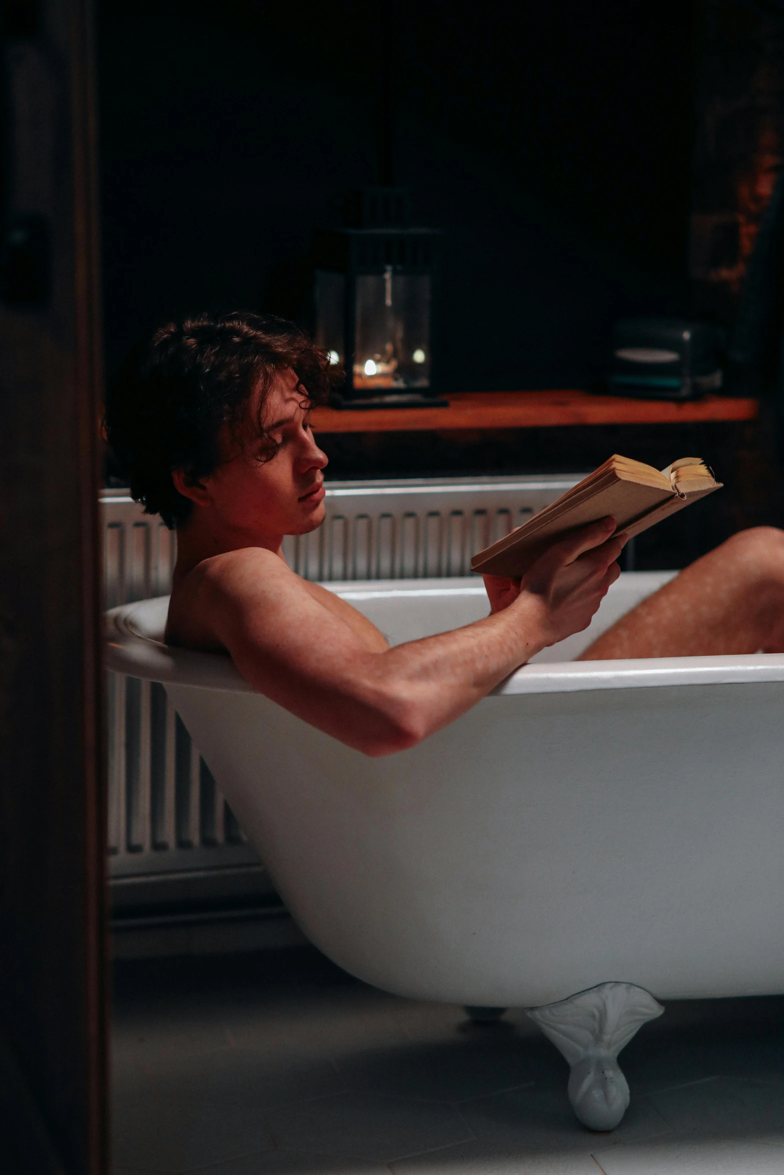 a man sitting in the bathtub holding a book