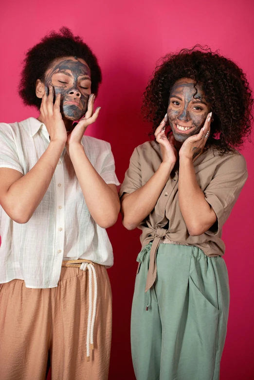 two woman with painted face make - up, each holding their hands together