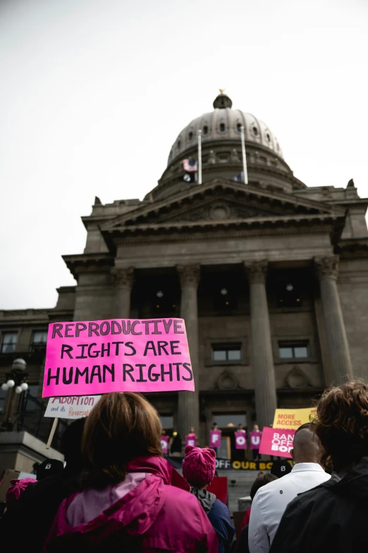 people gathered in front of a building holding signs