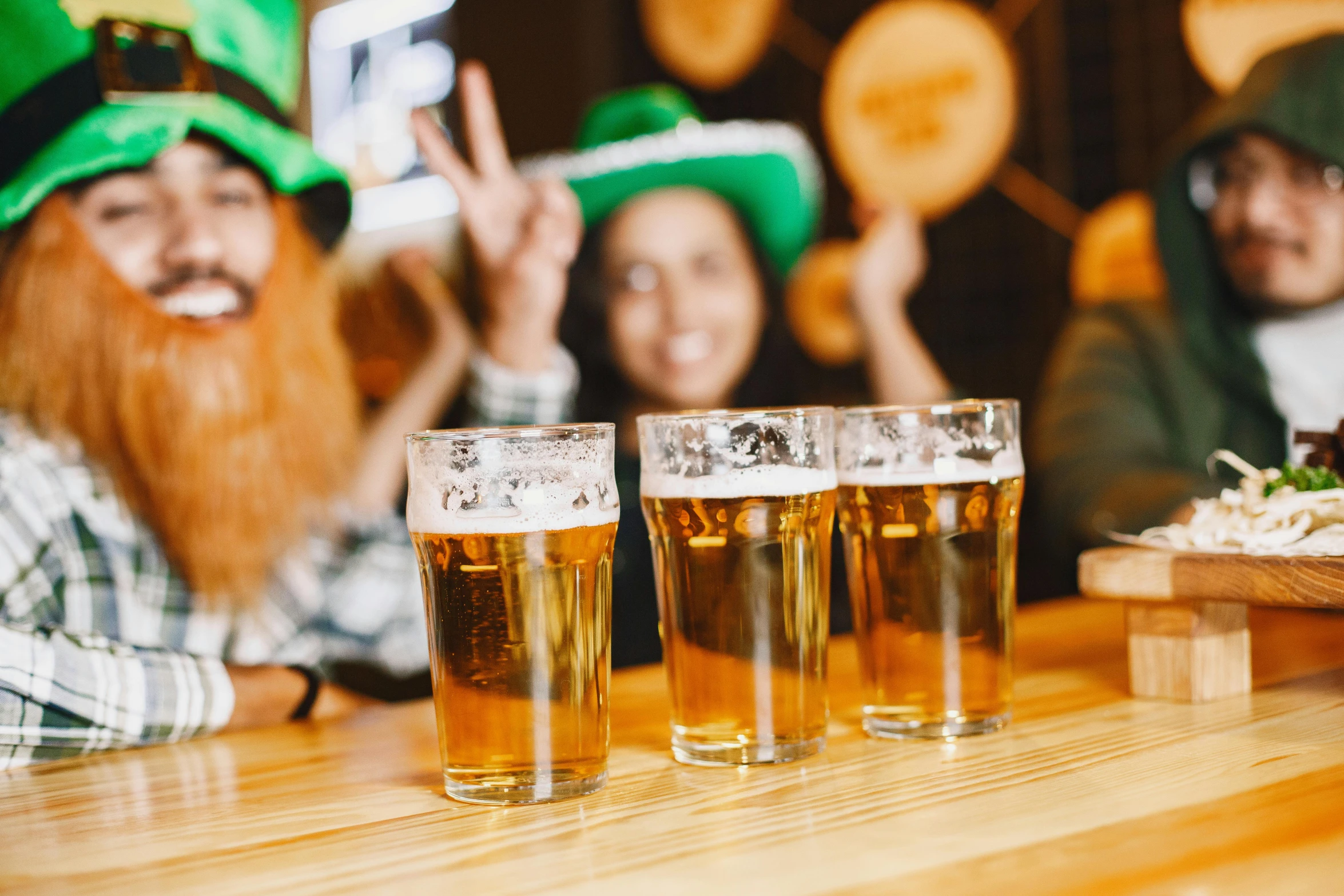 several people wearing green hats and glasses of beer