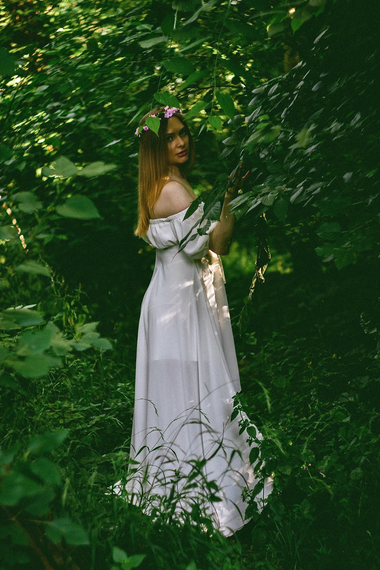 a girl standing in the woods looking at soing