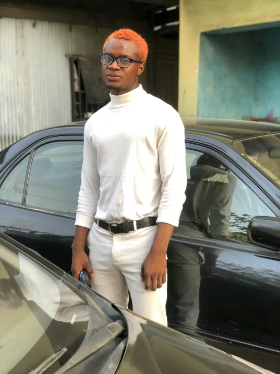 young black man standing next to his black car