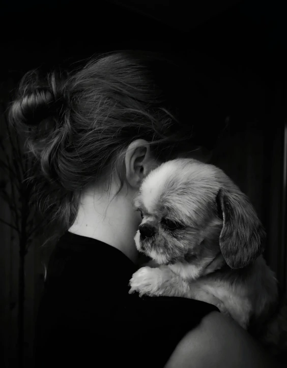 a woman holds a small dog up to her face