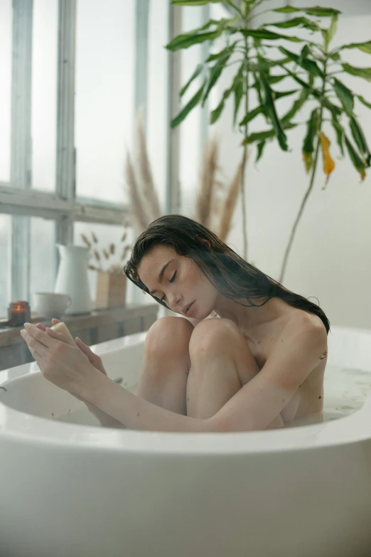 a beautiful woman in a tub looking at her cell phone