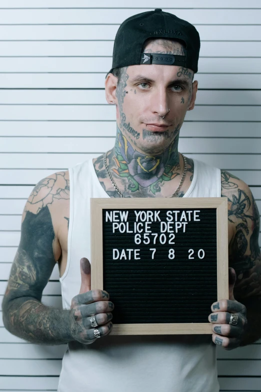 a tattooed man with a framed sign in front of him