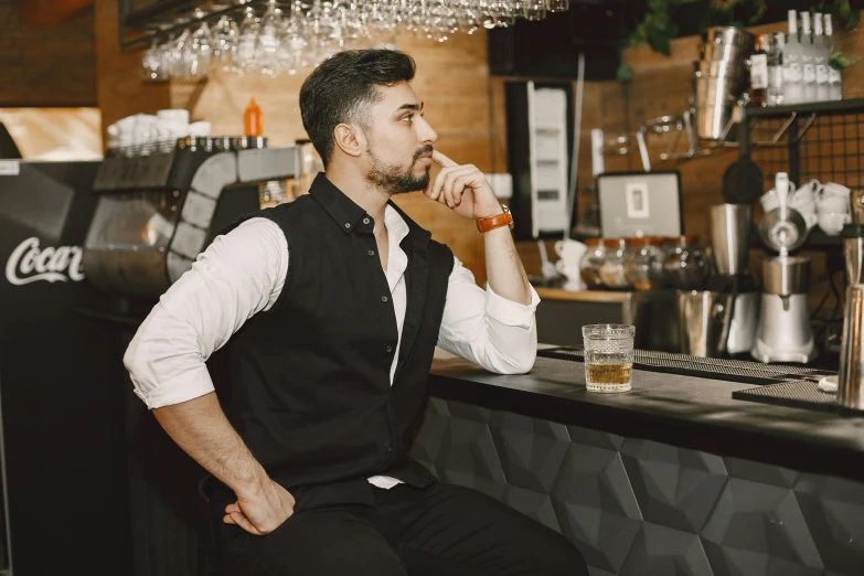 a man sitting at a bar with an orange drink in his hand