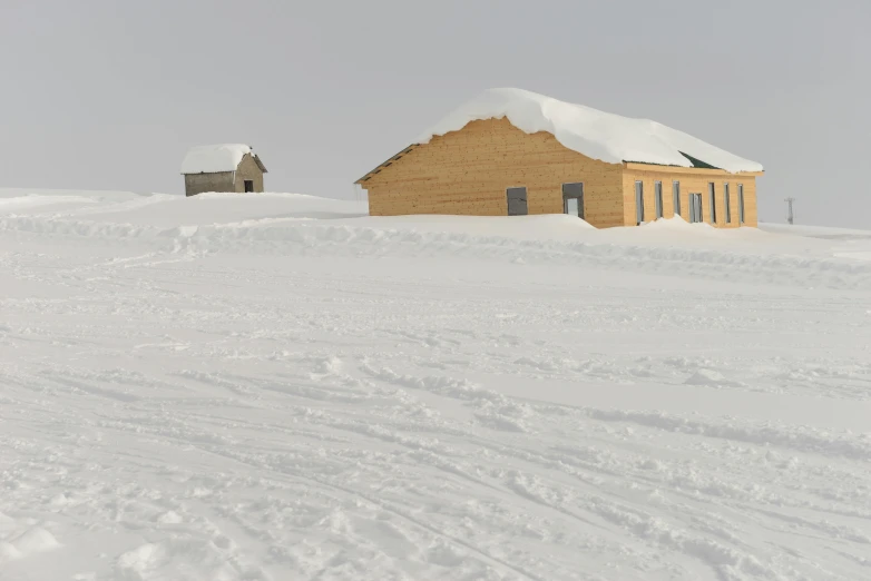 the snow covered hillside shows a cabin and two barns