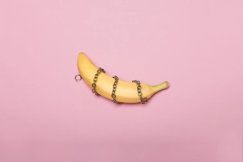 a banana on a chain on a pink background