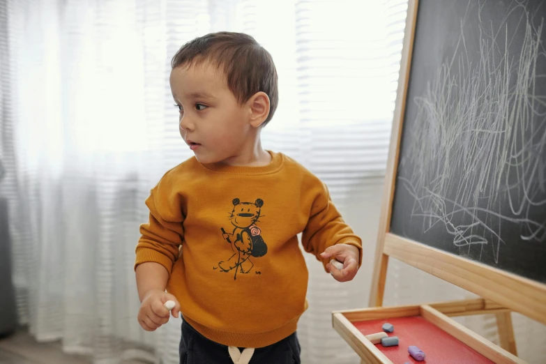 a toddler in front of a blackboard playing with magnets