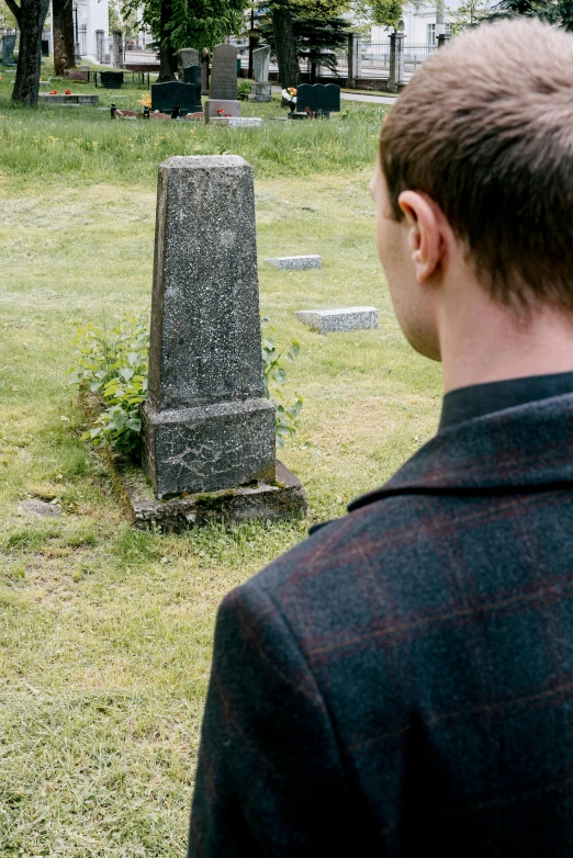 a man standing in front of a cemetery, looking at a monument