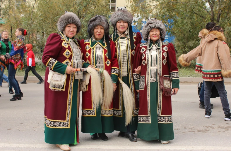 four people in long dresses are standing on a road