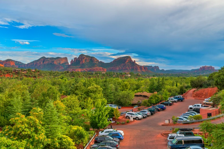 cars parked in the driveway next to tall red rocks