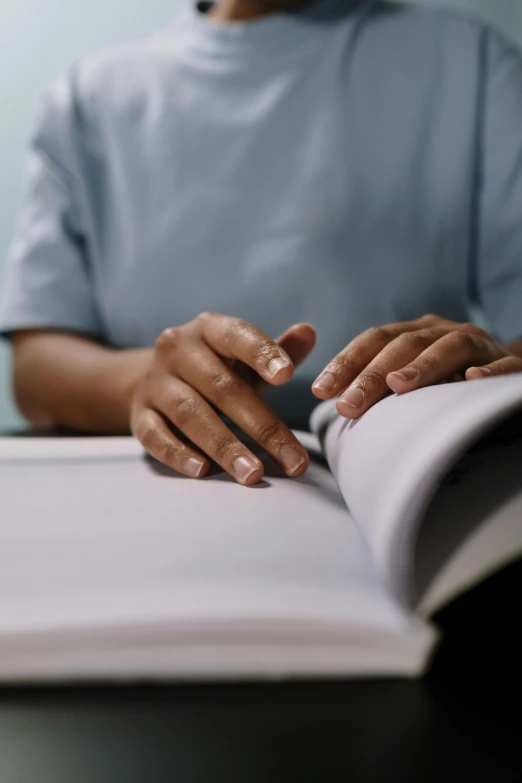 person sitting down reading a book on a table