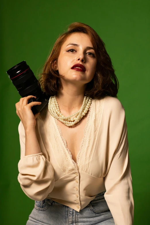 woman holding a camera up to her face in front of a green background