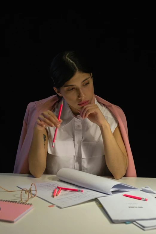 a woman sitting at a table with a pencil and a notebook