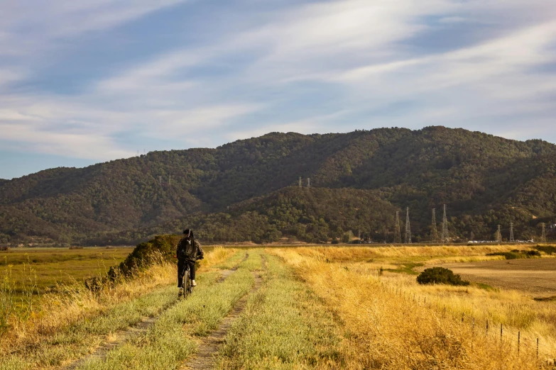 two people riding bikes on a road near a mountain