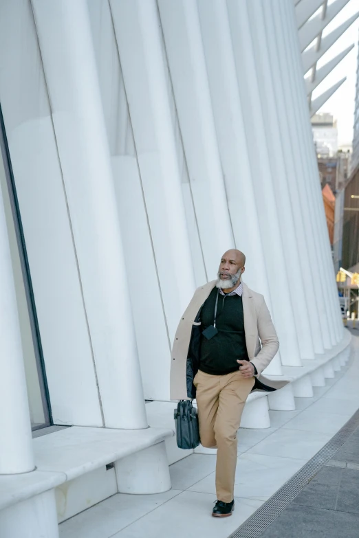 a man with a beard and a black top in front of a large building