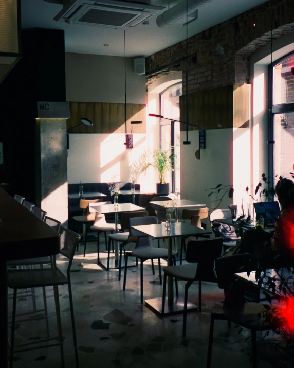 a restaurant with chairs and windows lit by sun through the windows