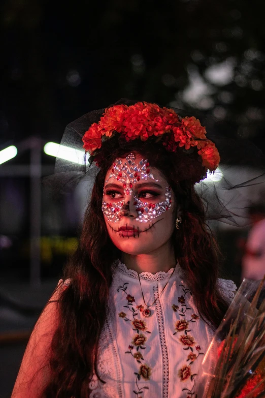 a woman with makeup, makeup, and flower crown holding flowers