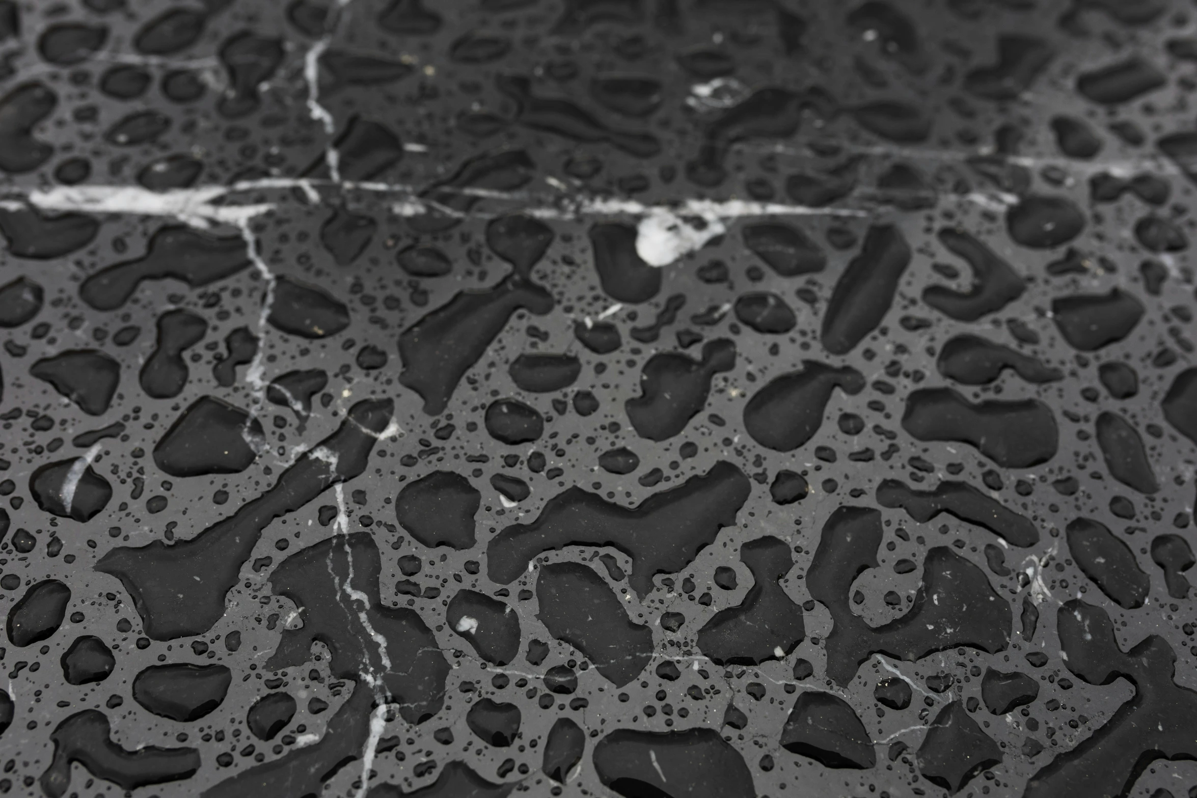 rain drops of water running down the side of a black floor