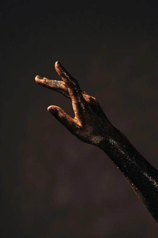 two hands in gold and black glitter with their fingers spread out