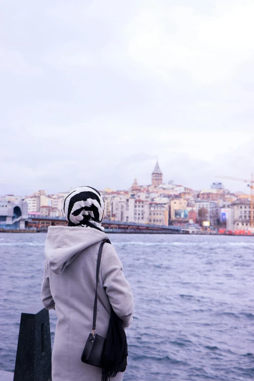 a person wearing a hat standing by a body of water