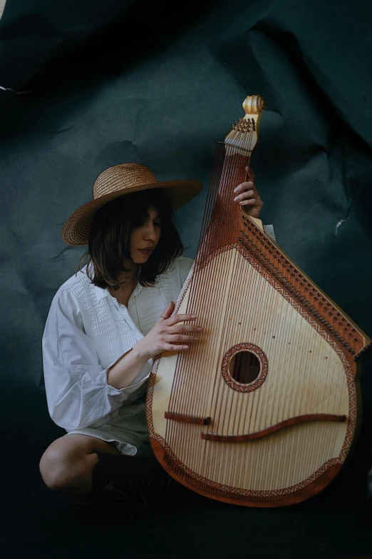 a woman in straw hat playing a long lute