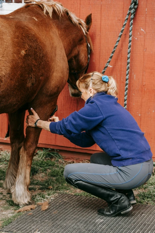 a woman is tending to her horse outside