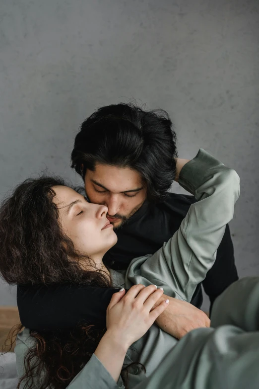 a man and woman hug while laying on a bed