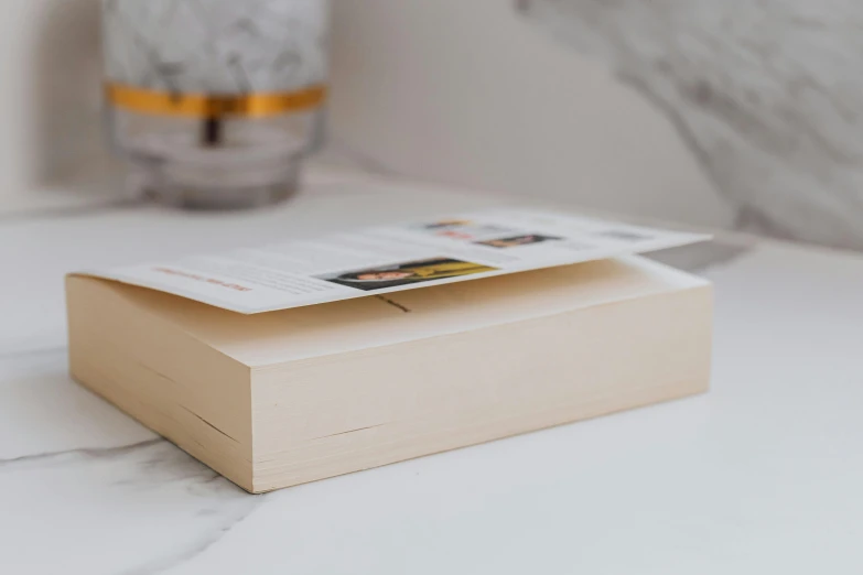 a book with one page missing sitting on the table next to a glass vase