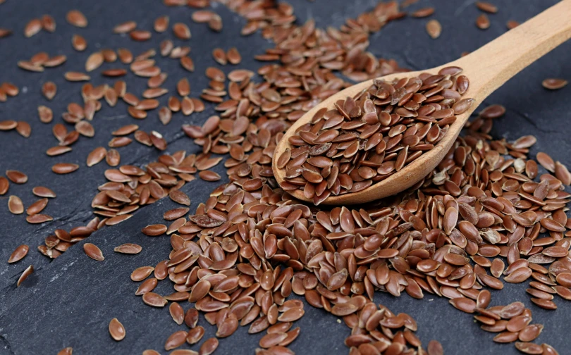 the seeds of a plant are shown next to a wooden spoon