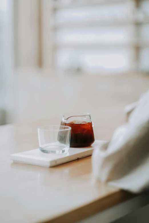 a square coaster with a cup and some juice