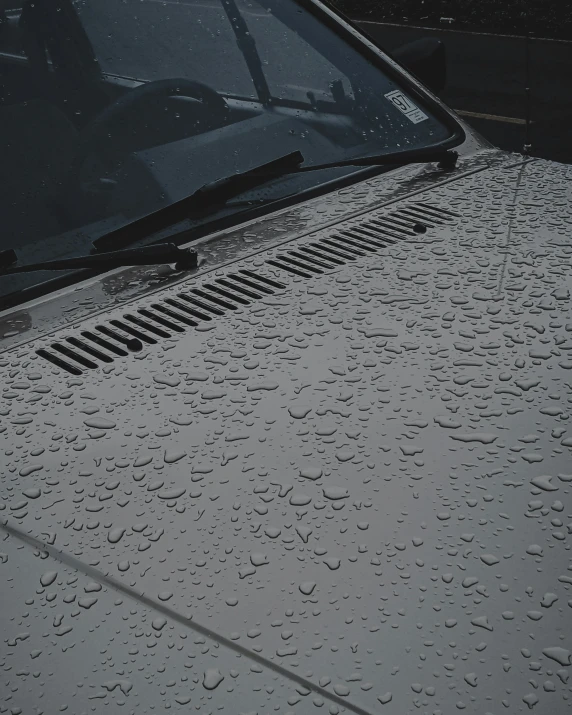 raindrops are covering the windows and rear of a black car