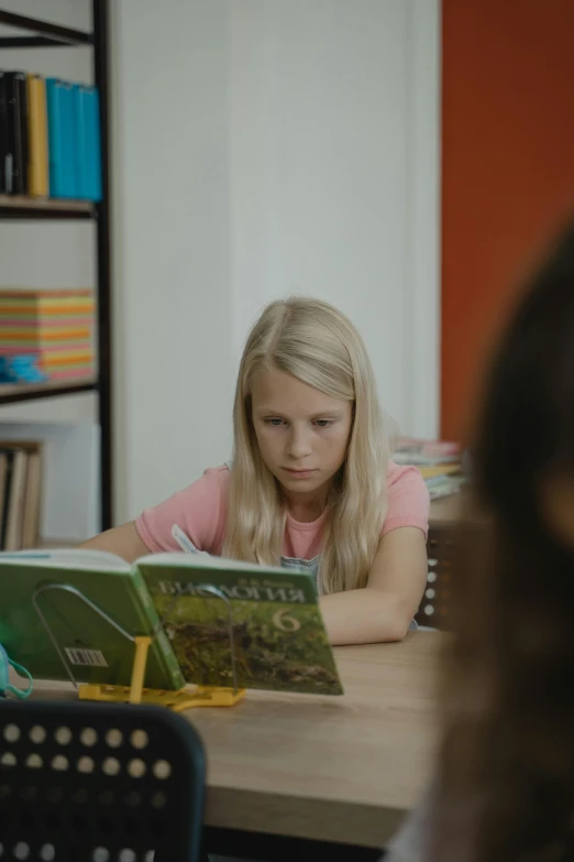 girl sitting at table with book open next to desk