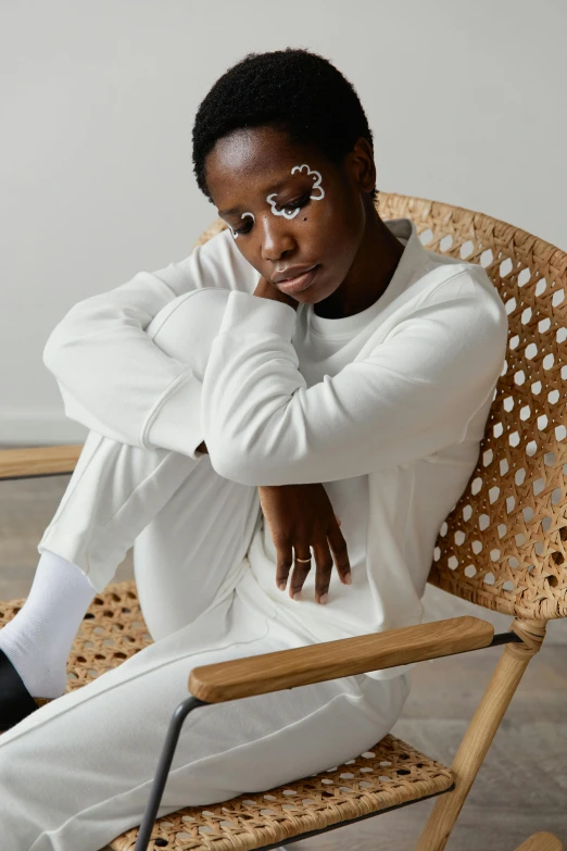 a young black woman with glasses and a shirt sitting in a chair