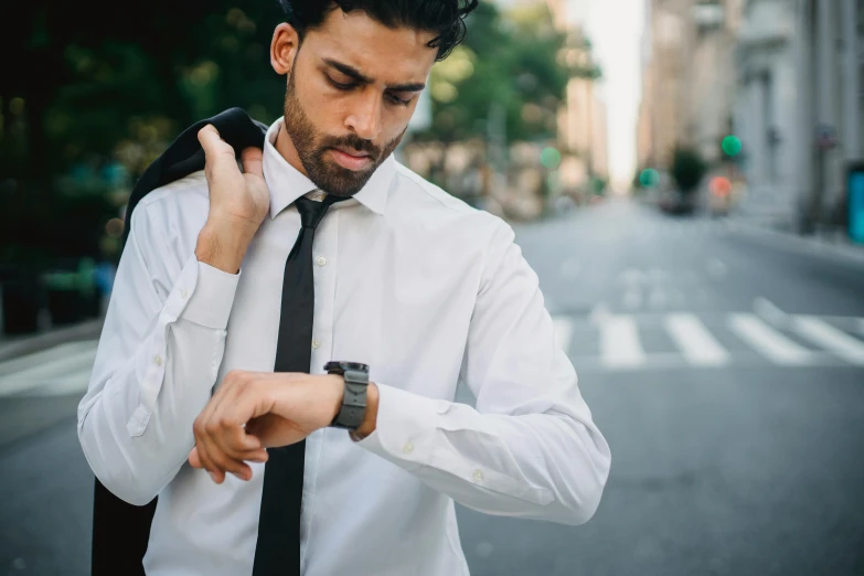 a young man is dressed in all white as he looks at his watch