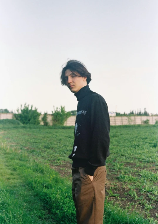 a man standing in the grass wearing a jacket