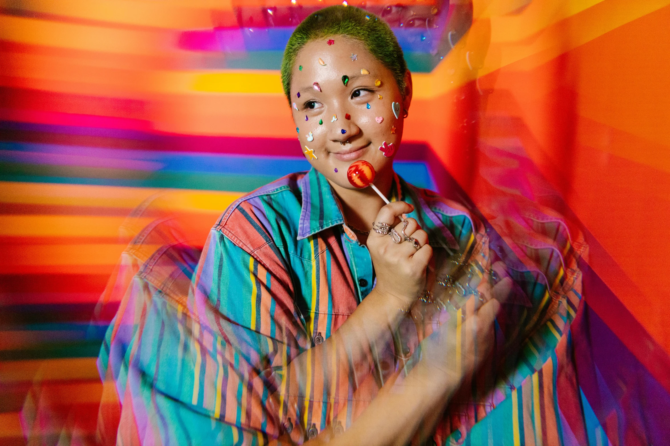 a woman with clown make - up and face paint on posing in front of an abstract background