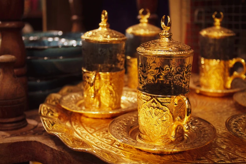 there are three golden tea pots on plates