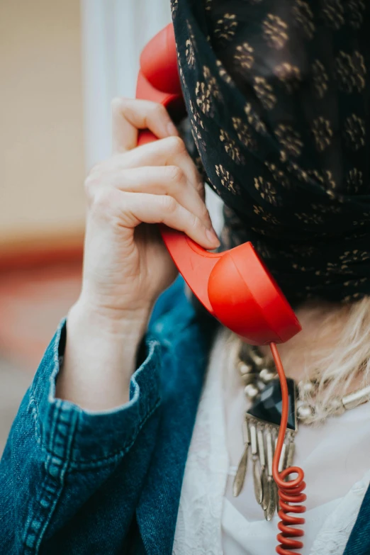 the woman has a scarf over her head talking on a red phone