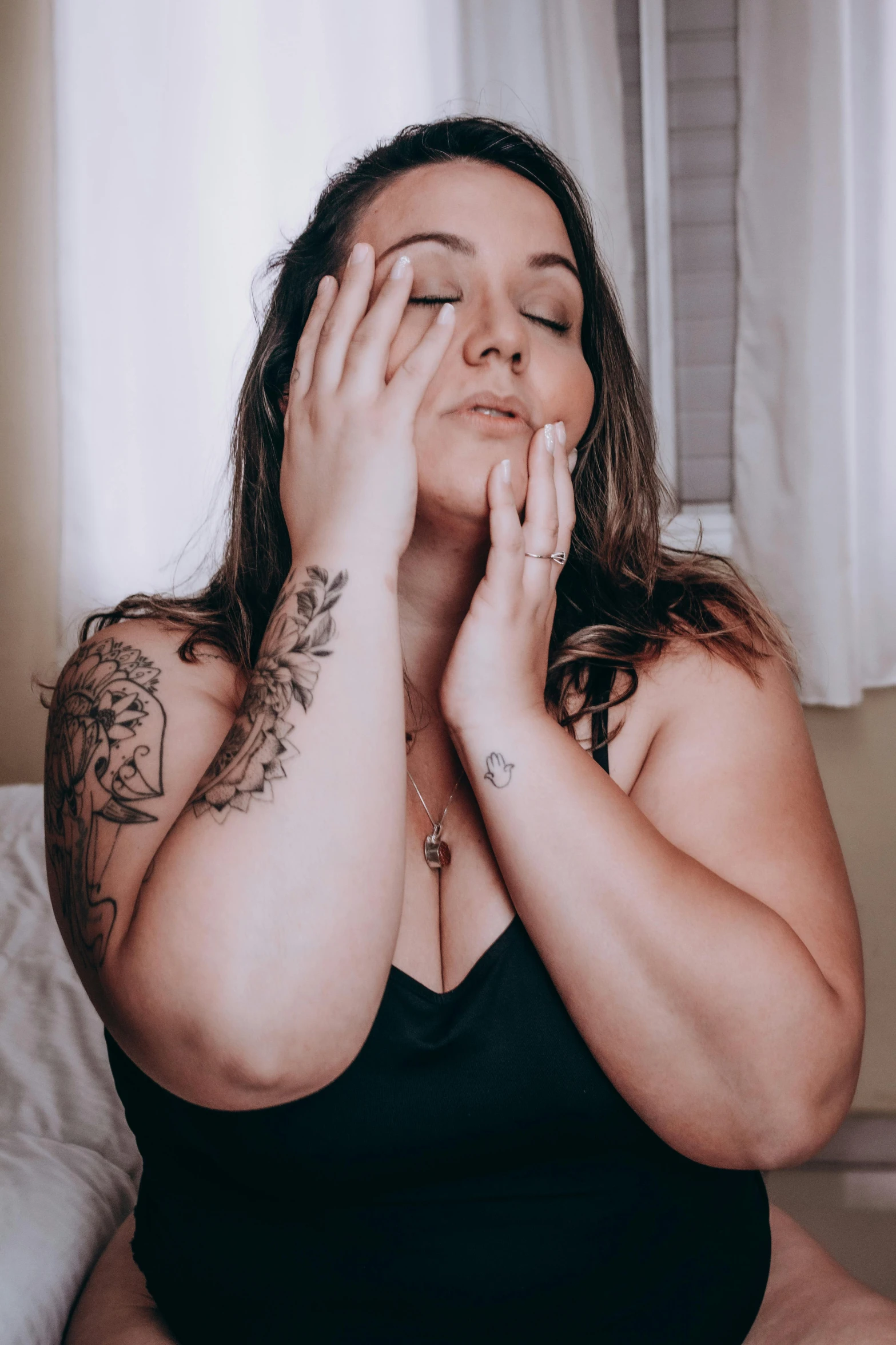 woman in black dress sitting on bed touching her hands