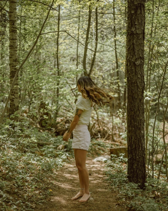 woman walking through woods in white dress