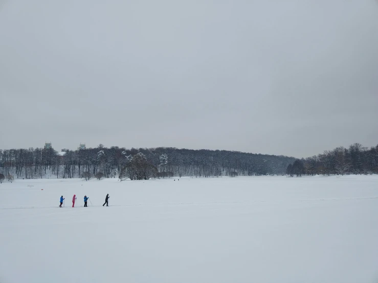 five people in the snow walking across an open field